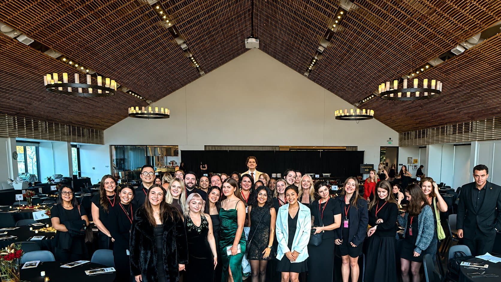 Hudson Crum standing at the center back of a banquet hall full of volunteers at a gala event